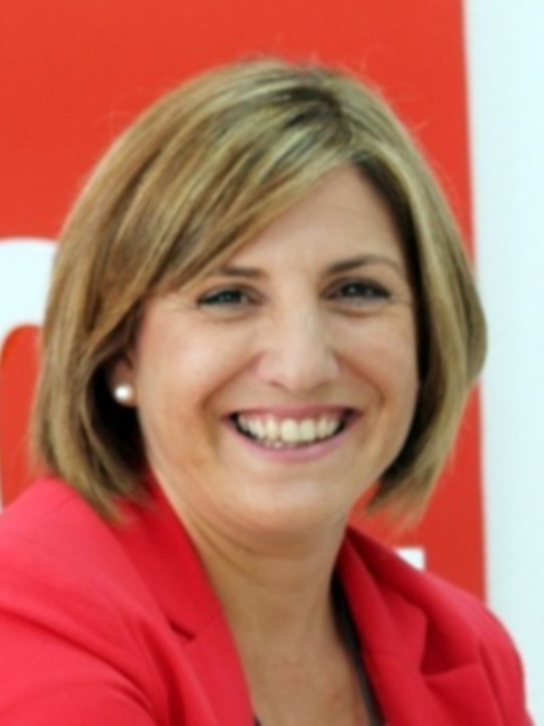 Una mujer sonriendo frente a un fondo rojo.
