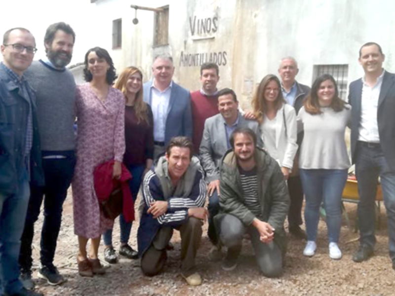Grupo de personas posando frente a una pared con la inscripción 'Vinos Amontillados'.