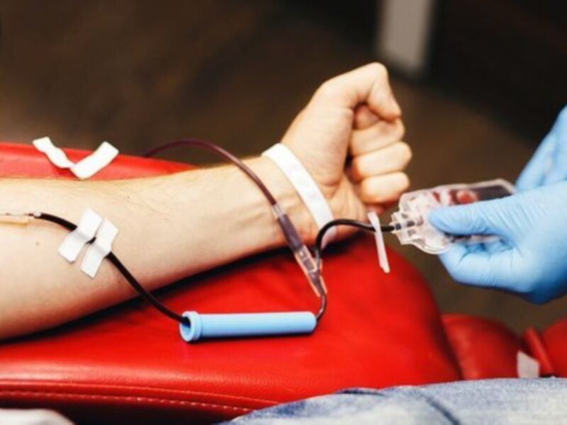 Donación de sangre: Una mano dona su sangre mientras un profesional la recoge con guantes azules.
