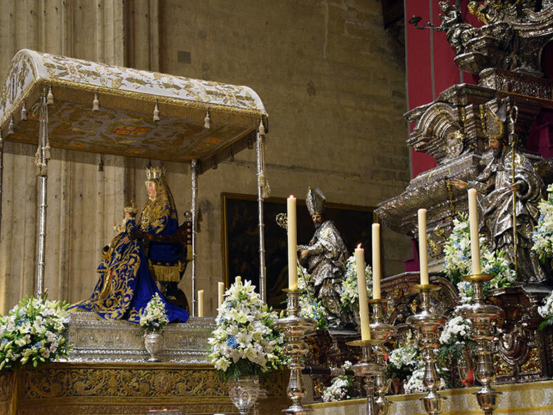 Altar ornado con estatuas religiosas, flores y candelabros en una iglesia.