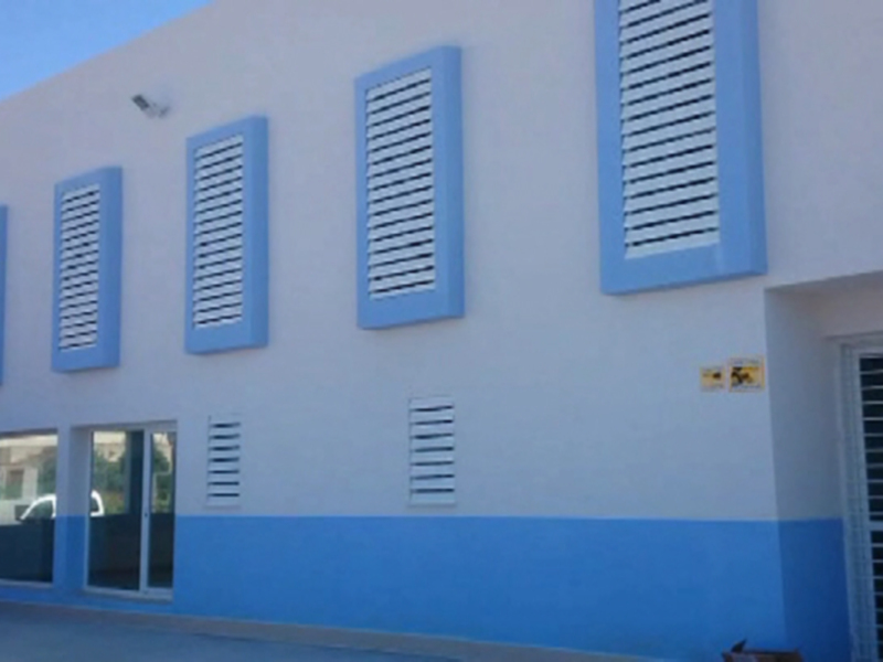 Edificio blanco con ventanas azules y marquesina amarilla.