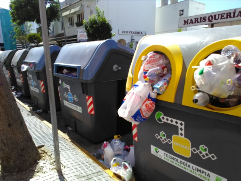 Contenedores de reciclaje en una calle con etiquetas de tecnología de limpieza y colores distintivos.