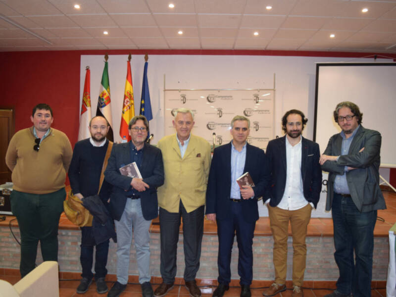 Grupo de personas posando frente a una pantalla con banderas españolas y portuguesas.