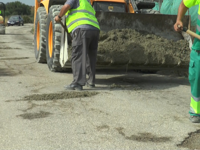 Trabajadores de mantenimiento de carreteras reparando una carretera con maquinaria pesada.
