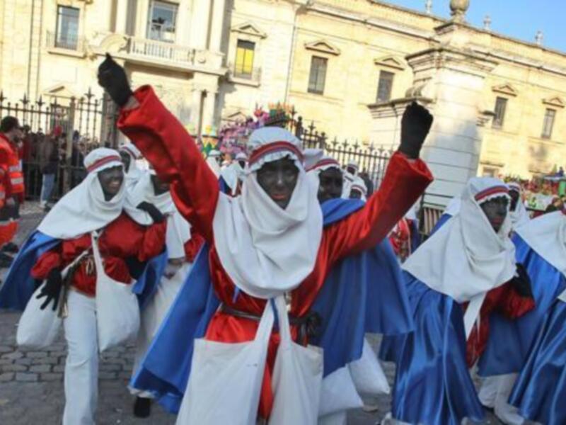 Un grupo de personas vestidas con trajes tradicionales participa en una celebración frente a un edificio histórico.