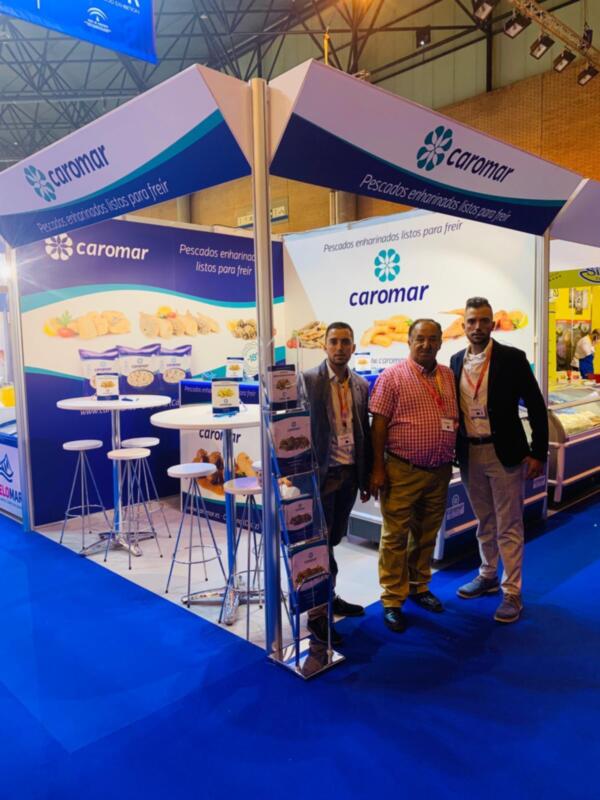 Exposición de Caramar en un evento comercial con stands azules y blancos, mostrando productos de pescado.