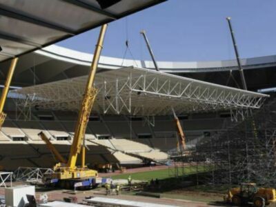 Estadio en construcción con grúas y estructuras metálicas.