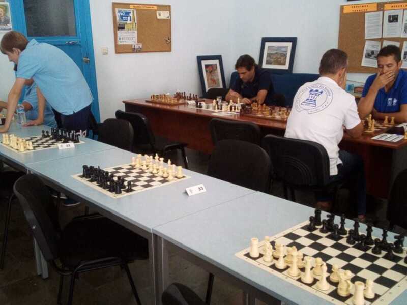 Jugadores de ajedrez en una sala de juego, con mesas y tableros de ajedrez organizados para un torneo.