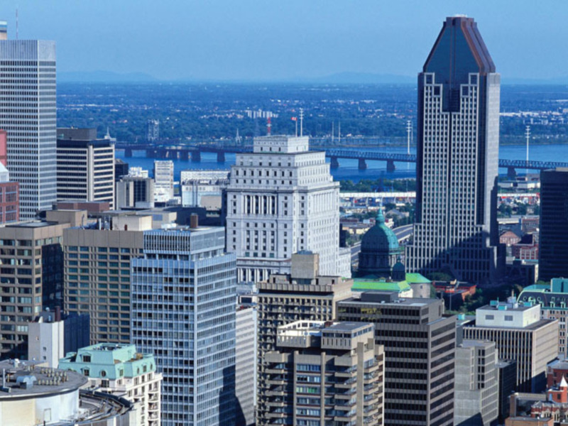Vista panorámica de Montreal con edificios modernos y el río Saint Lawrence en el fondo.