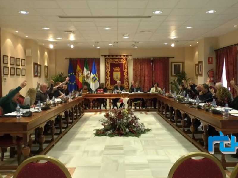 Sala de reuniones con mesas largas, sillas rojas y banderas europeas.