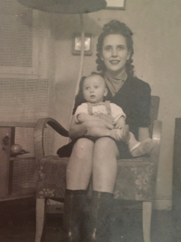 Una mujer sostiene a un bebé mientras se sienta en una silla, retrato familiar de la década del 40s.