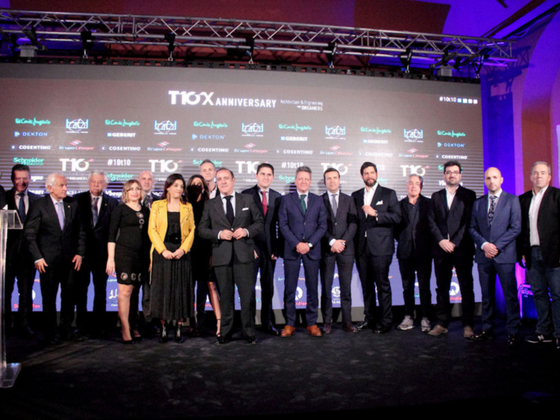 Celebración del 10º aniversario de una empresa en un evento formal con una gran pantalla en el fondo mostrando logos de diferentes empresas.