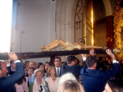 Procesión religiosa con la imagen del Cristo en un entorno eclesiástico, con fieles participando.