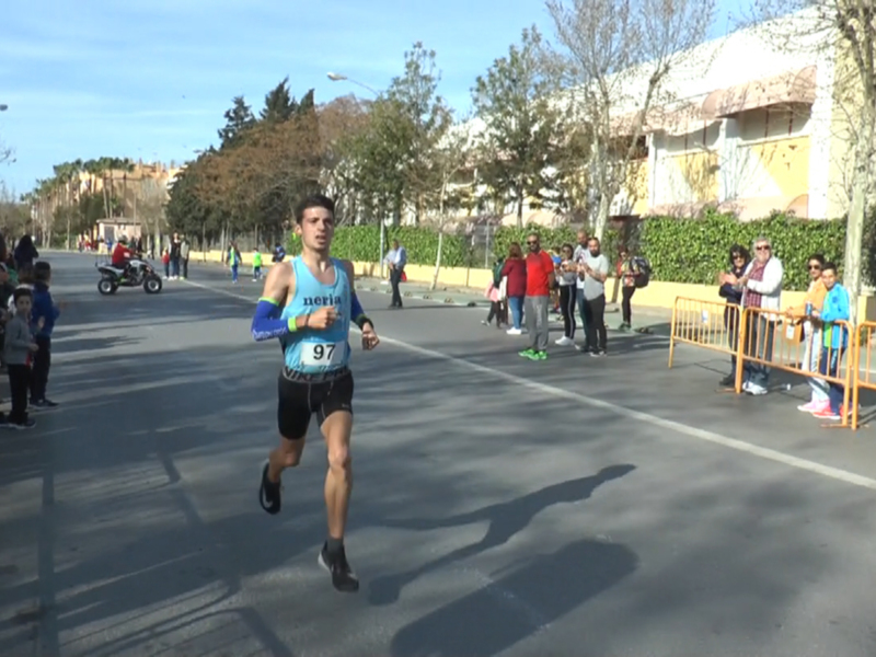 Un corredor en medio de una carrera urbana, con un número 92 en su camiseta. La imagen muestra a varios espectadores al borde de la calle, con árboles y edificios en el fondo.