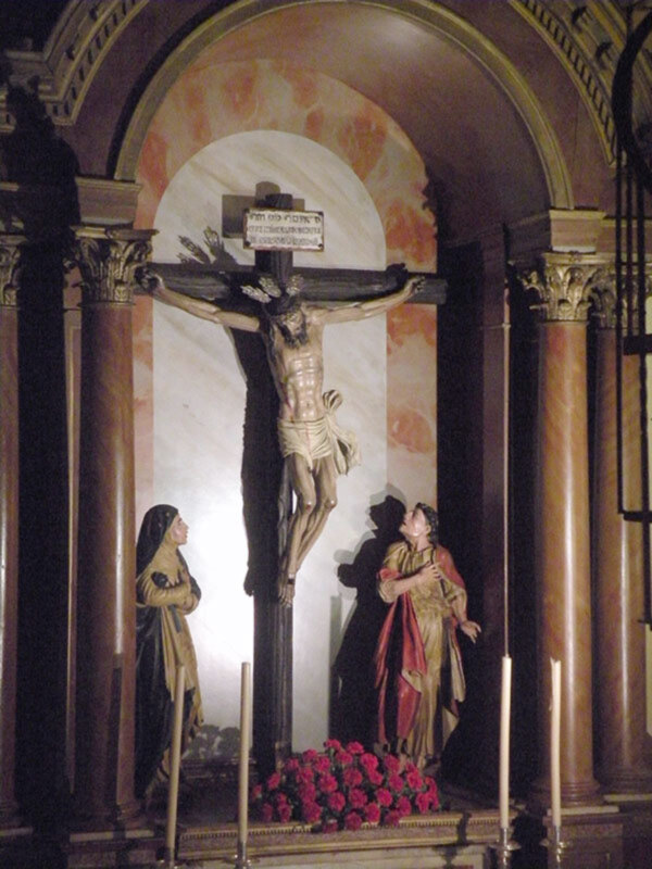 Crucifixion scene with statues and flowers in a church.