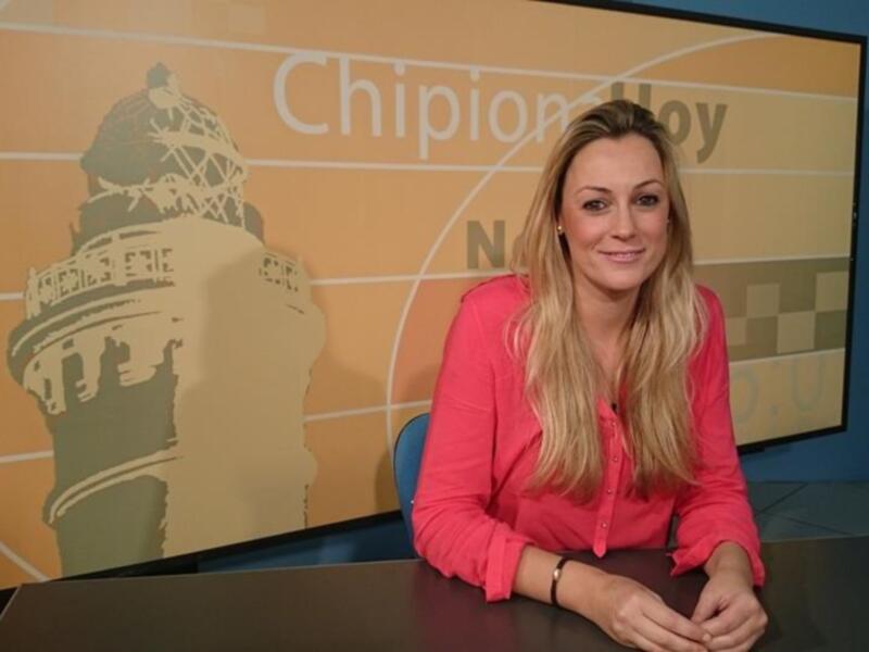 A una mujer sentada frente a un fondo con el título "Chipionial Hoy" y una imagen de un edificio. La mujer está sonriendo y parece estar en una transmisión o programa informativo.