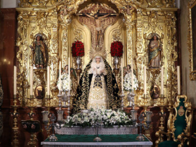 Altar dorado con estatuas religiosas y flores blancas.