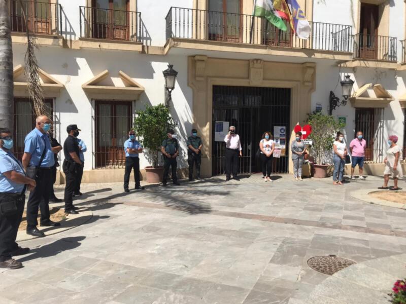 Persona de autoridades y policías en una reunión frente a un edificio municipal.