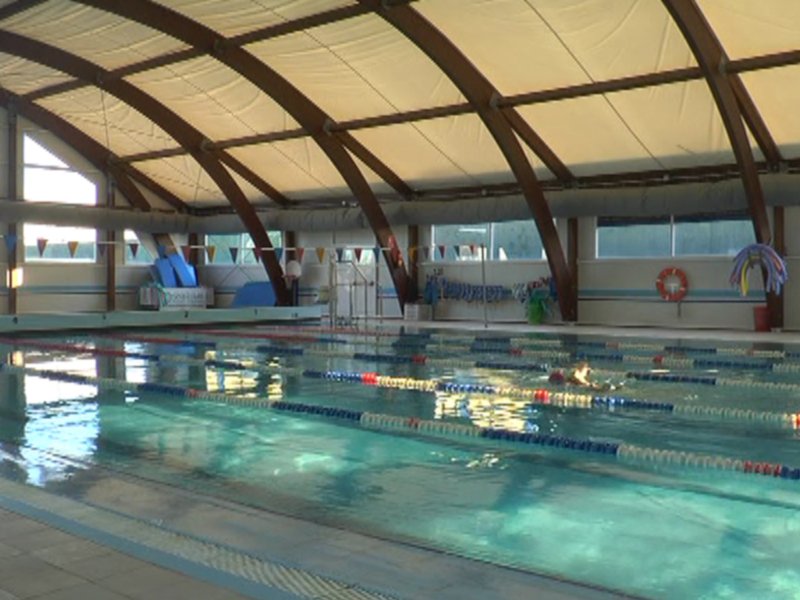 Piscina interior con natación sincronizada, paredes azules y líneas de división en el agua.