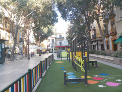 Jardín infantil en la calle, con juegos de colores y árboles.