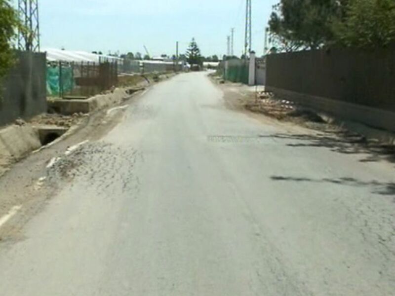 Carretera sin pavimentar con algunas áreas de asfalto y restos de construcción.