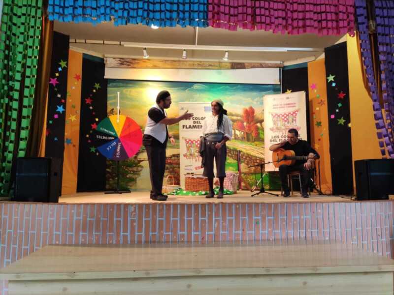 Escenario festivo con decoración colorida y un cartel promocionando el flamenco para niños y jóvenes.