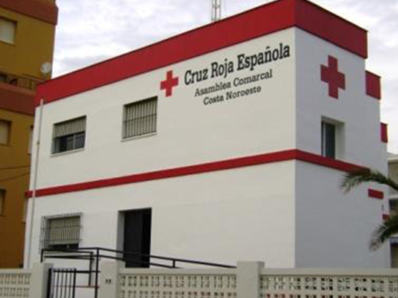 La sede de la Cruz Roja Española en Costa Noroeste, una organización benéfica dedicada a la ayuda y el rescate en situaciones de emergencia. La construcción es moderna, con una fachada principal de color blanco y rojo, y se encuentra rodeada por edificios residenciales.