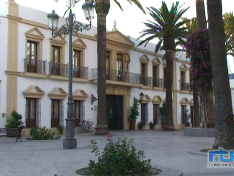 Plaza con palmeras y edificios blancos en el fondo.