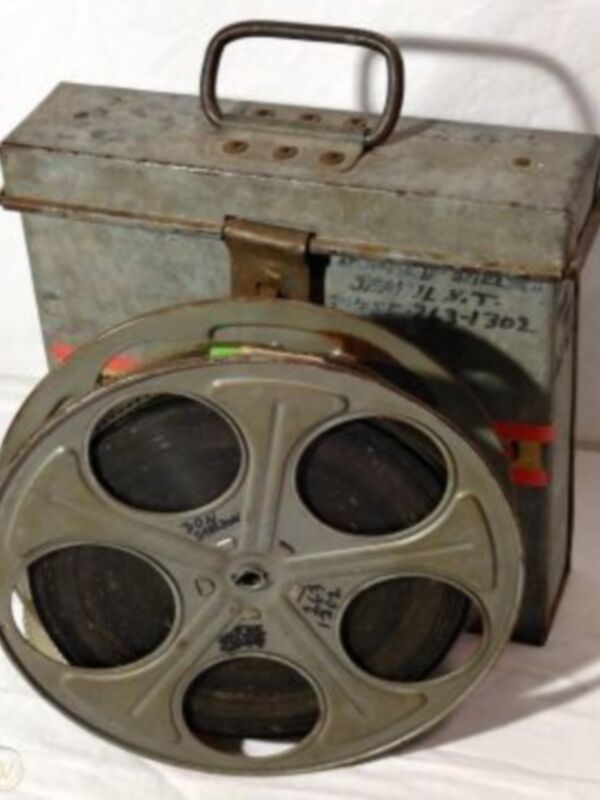 Un viejo reproductor de película de 8 mm en su caja metálica. La caja tiene un número de serie visible.