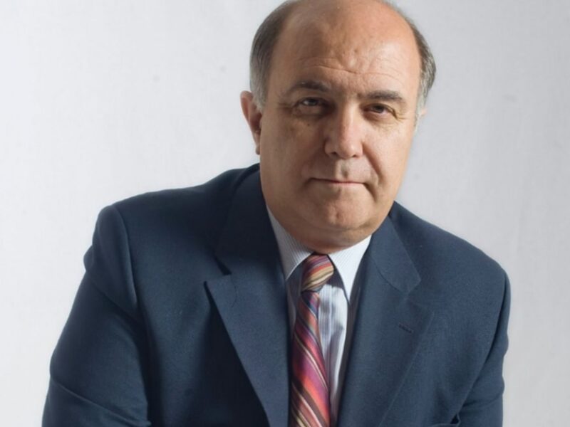 Retrato de hombre en traje y corbata, fondo blanco.