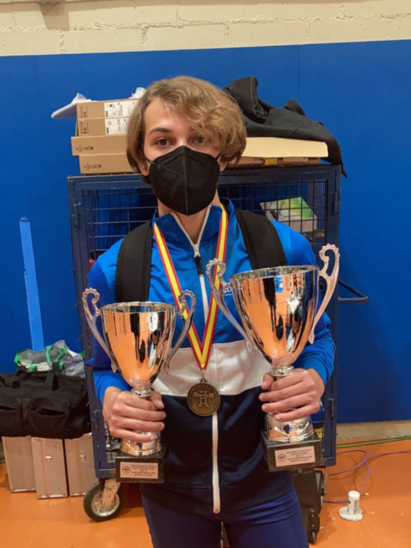 Joven celebrando con dos trofeos y una medalla tras un éxito deportivo.