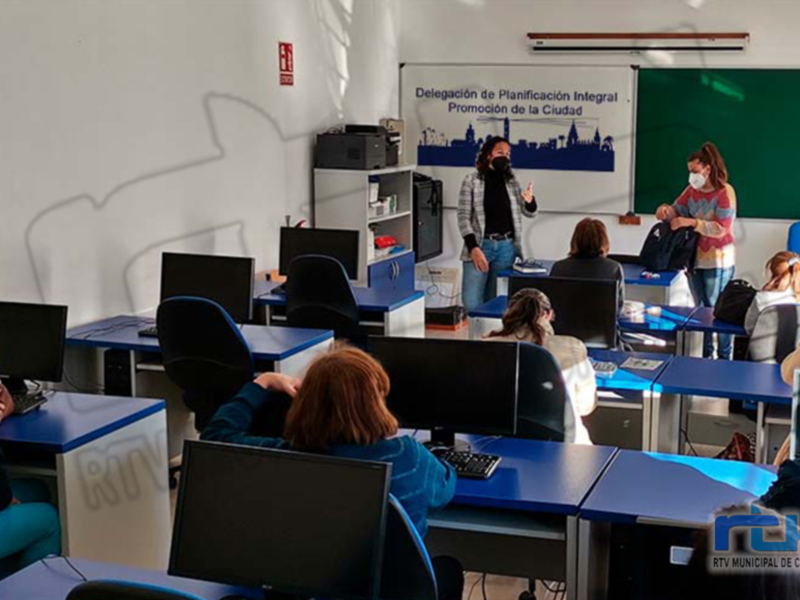 En una aula, estudiantes con máscaras se concentran en un aula con computadoras y carteles informativos. La imagen muestra una escena educativa en un entorno moderno, enfocada en el aprendizaje y la formación.