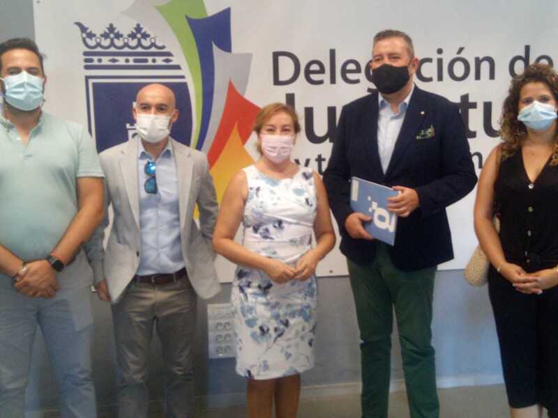 Equipo de trabajo en una reunión formal, todos con mascarillas, frente a un fondo con el logotipo de la Delegación de la Junta de Andalucía.