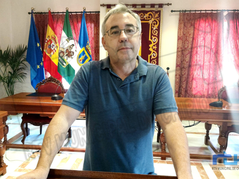 Un hombre en una sala de conferencias con banderas de España y la UE en el fondo.