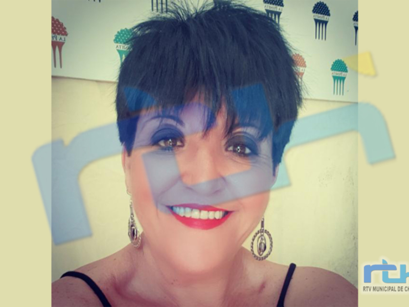 Retrato de una mujer sonriente con maquillaje y joyería, fondo con logotipo de RTV Municipal de Chipiona.