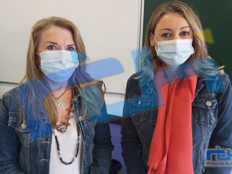 Dos personas con máscaras faciales, posiblemente en una sala de espera o centro médico.