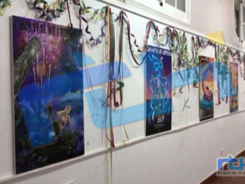 Una colección de carteles colgados en una pared, probablemente relacionados con un festival o evento cultural. Los carteles presentan diseños variados y colores vibrantes, destacando la diversidad de temas y estilos. La pared es blanca, lo que hace que los colores brillen aún más.