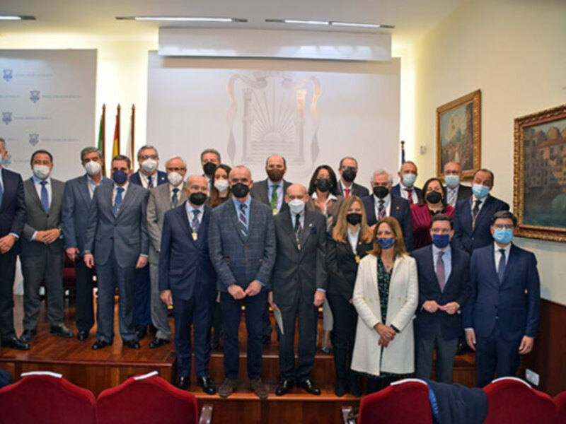 Gruppo di persone in una sala ufficiale indossano mascherine, posano per una foto di gruppo.