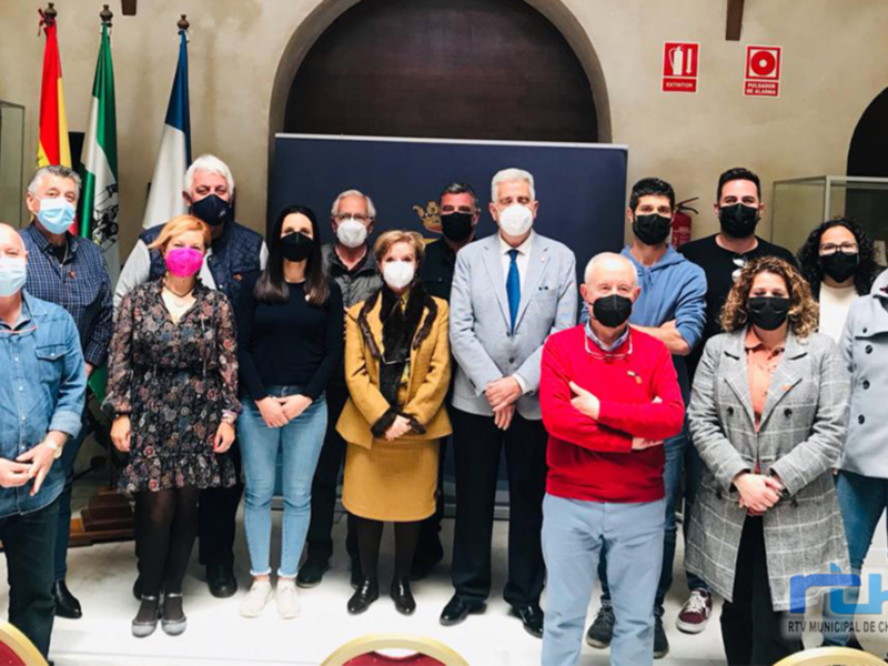 Una reunión formal en un edificio oficial, con personas vestidas formalmente y usando mascarillas, posiblemente en un contexto político o gubernamental.