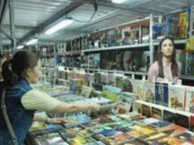 Personas en una tienda de comics, mostrando una variedad de cómics en estanterías.