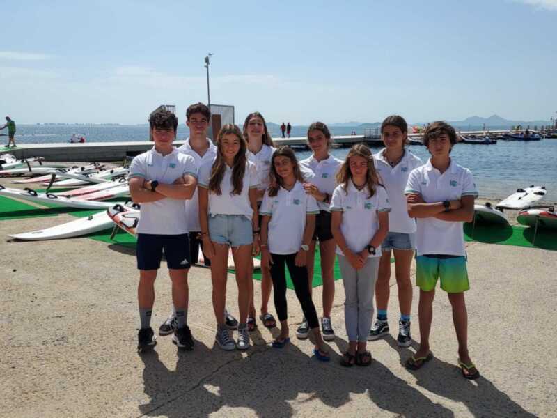 Equipo de jóvenes en un puerto deportivo, listos para actividades náuticas.