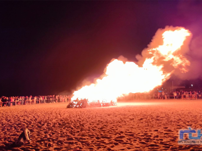 Fuego gigante en la playa de noche, con espectadores a lo lejos. Imagen tomada por @MCH.