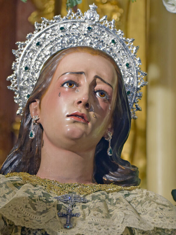 Venerada imagen de la Virgen con corona de diamantes y detalles ornamentales en un entorno religioso.