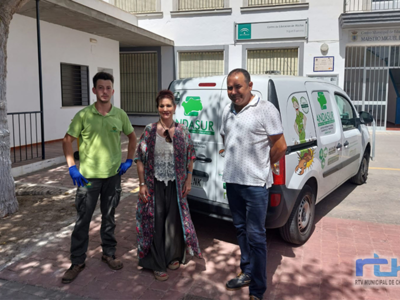 Tres personas posan frente a una furgoneta de limpieza, con un edificio en el fondo.