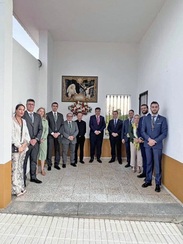 Grupo de personas posando en una entrada con una imagen religiosa en el fondo.