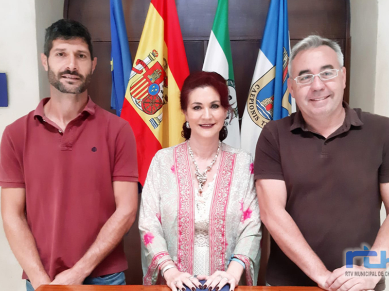 Tres personas posando en una oficina con banderas españolas y regionales al fondo.