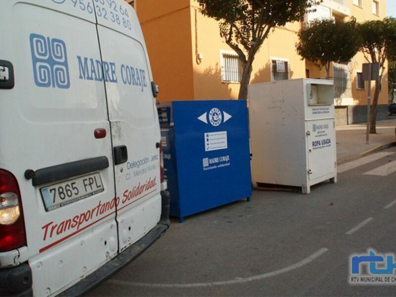 Un camión blanco de 'Madre Coraje' y contenedores de reciclaje en una calle urbana.