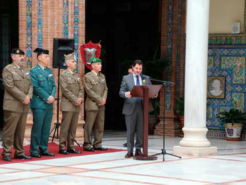 Oficial en uniforme militar hablando en un acto oficial en un patio con columnas y azulejos decorativos.