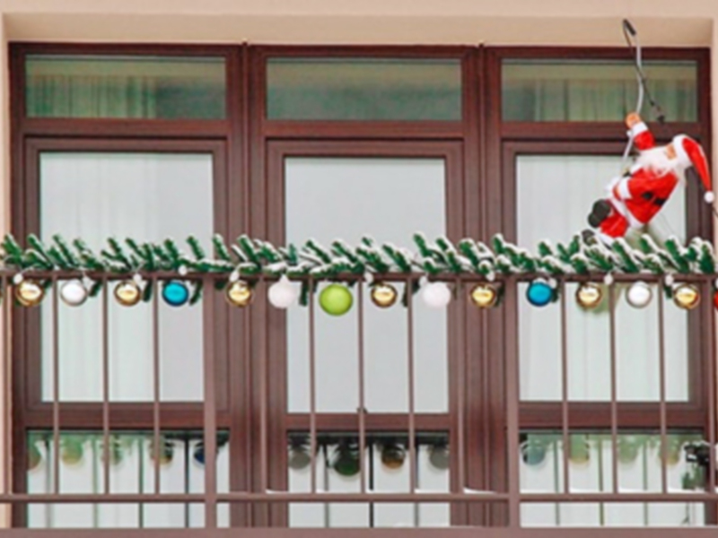 Puerta de madera con ventanas y decoración navideña con adornos colgantes.