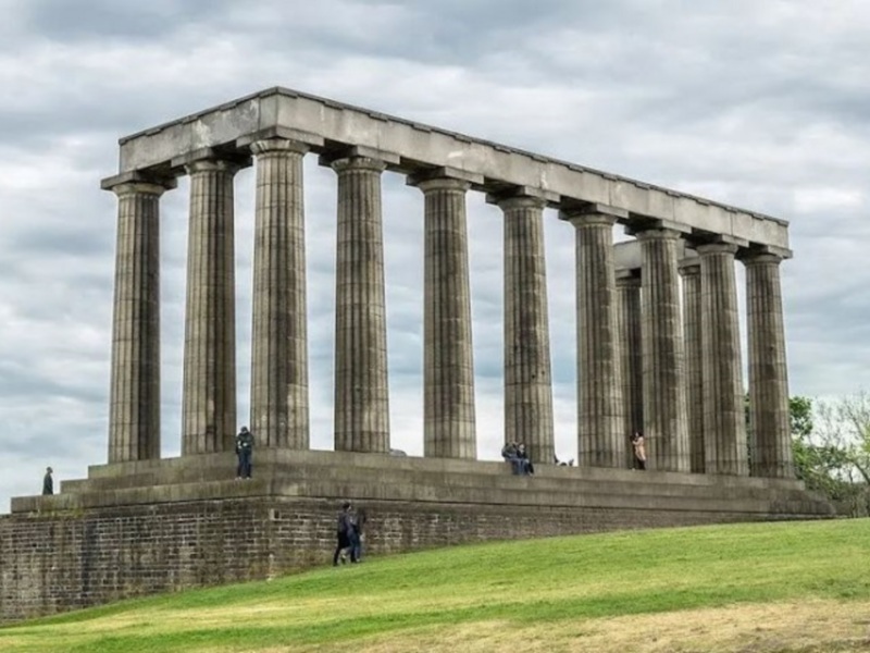 Monumento Nacional de Escocia, Edimburgo, con columnas griegas y visitantes en un día nublado.